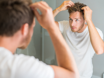 guy styling hair in mirror
